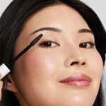 Woman putting tubing mascara from jane iredale on her eyelashes